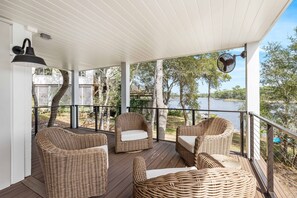Área externa coberta com móveis de vime e vista para um lago.