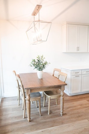 A dining area with a wooden table, chairs, a potted plant, and a pendant light fixture. - Bella Vista | Lakefront 30A | Dock & Kayaks (Seacrest)
