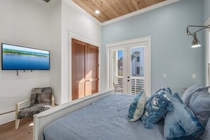 A bedroom with a bed, a chair, a television, and a view of the outdoors. - Blue Fin | Heated Pool | Sleeps 26 | Near Rosemary Beach (Inlet Beach)
