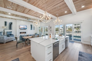 A spacious living area with a large island, a dining table, and a kitchen with a dishwasher. - Blue Fin | Heated Pool | Sleeps 26 | Near Rosemary Beach (Inlet Beach)