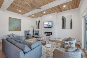 A modern living room with a sectional sofa, a fireplace, and a television. - Blue Fin | Heated Pool | Sleeps 26 | Near Rosemary Beach (Inlet Beach)