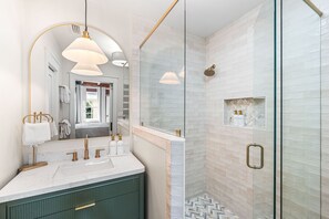 A modern bathroom with a glass shower enclosure, a vanity with a marble countertop, and a large mirror with a gold frame. - 🌞Coastal Chateau | Lakefront 30A Retreat | Dock, Kayaks & 4 Bikes | Sleeps 8 (Seacrest)