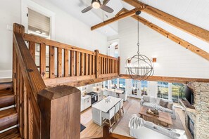 A spacious interior with a wooden staircase, a dining area, and a stone fireplace. - Coastal Vista 30A | Private Dock | 2 Homes (Seacrest)