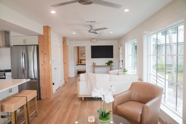 Eine moderne Küche mit einem Edelstahl-Kühlschrank, Holzschränken und einer Essecke mit Korbstühlen.