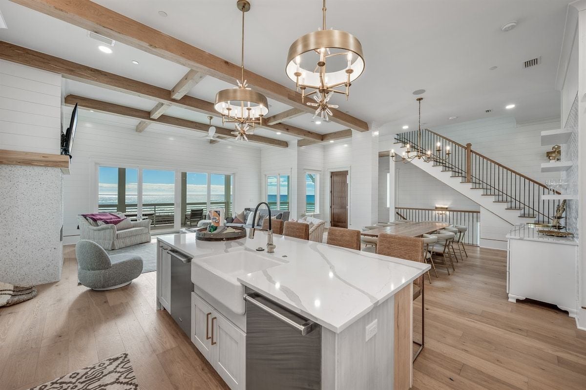 A spacious kitchen with a central island, wooden beams, and pendant lighting.