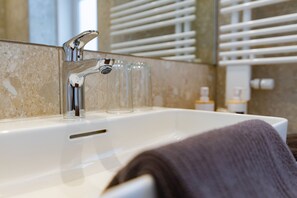 Ein Badezimmer mit einem weißen Waschbecken, einem Spiegel und einem Handtuch, das an der Seite hängt.