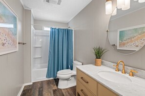 Ein Badezimmer mit Dusche, Toilette, Waschbecken und einem Blumentopf.