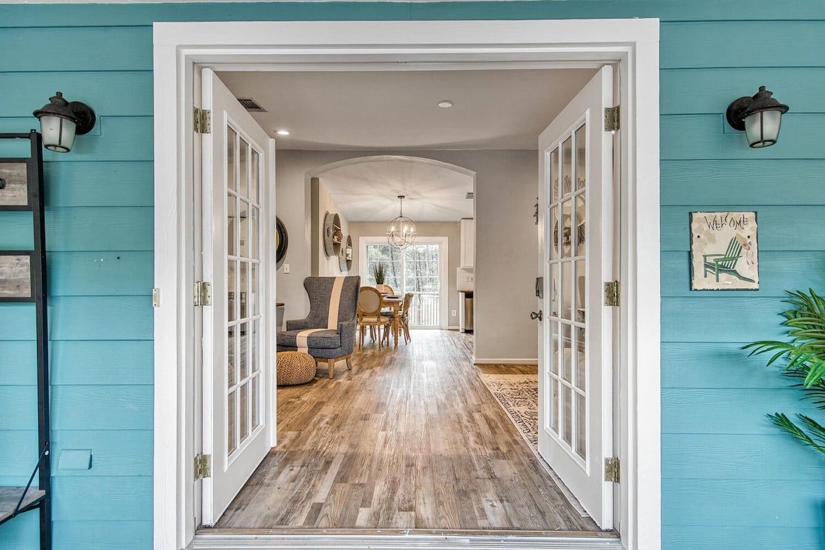 A hallway leading to a dining area with a chandelier, wooden flooring, and a view of the dining space.