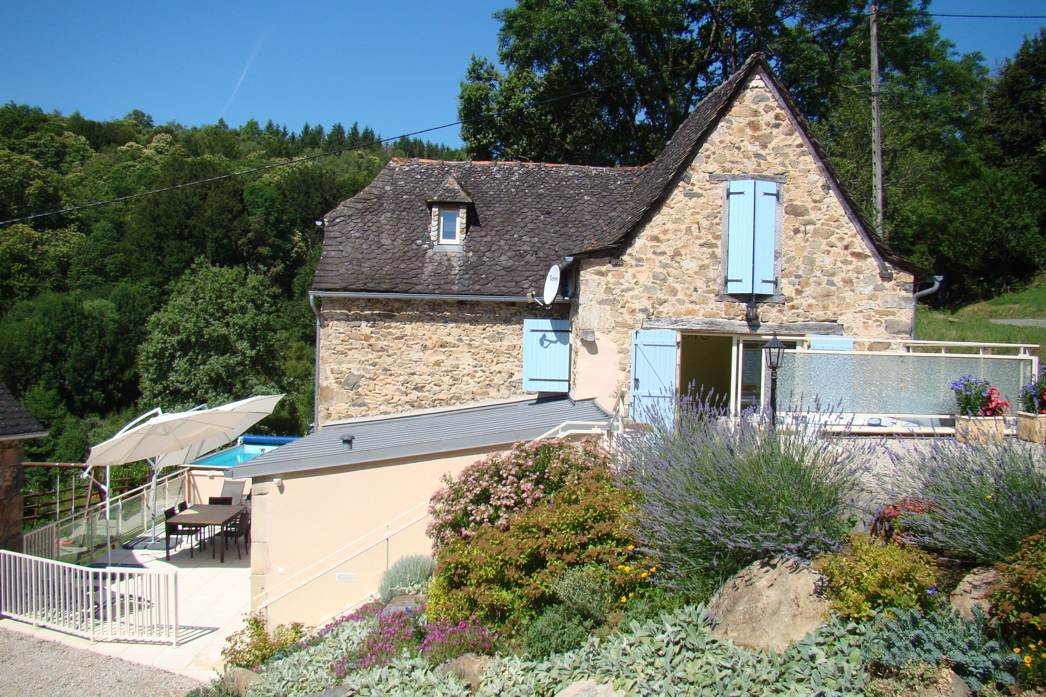 Une maison en pierre avec un toit en pente, une petite fenêtre et un balcon doté de sièges pour l’extérieur.