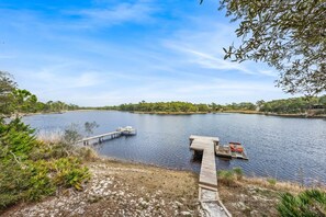 A calm lake with a wooden dock extending into the water, surrounded by trees and vegetation. - 🚲Lakeside Villa | Private Dock, Kayaks & Bikes | Minutes to 30A Beaches🏖️ (Seacrest)