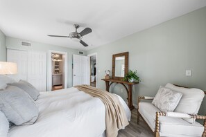 A bedroom with a bed, a chair, a bedside table, a mirror, and a ceiling fan. - 🚲Lakeside Villa | Private Dock, Kayaks & Bikes | Minutes to 30A Beaches🏖️ (Seacrest)