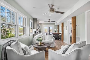 A spacious living room with a large window, a ceiling fan, and a view of the outdoors. - 🚲Lakeside Villa | Private Dock, Kayaks & Bikes | Minutes to 30A Beaches🏖️ (Seacrest)