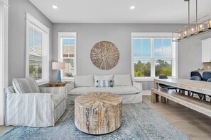 A modern living room with a round coffee table, a sofa, and a dining area with a bench. - ⭐Palms By The Sea | Rooftop Deck | 12,000 Sq Ft Pool | Beach Access⭐ (Seacrest Beach)