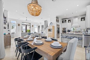 A spacious dining area with a wooden table set for a meal, surrounded by modern chairs. - Playa Maya | Pool | Steps to Rosemary | Sleeps 10 (Inlet Beach)