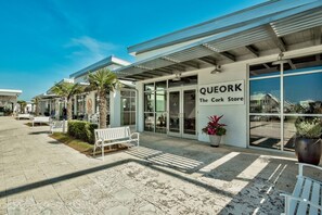Una fachada comercial con un letrero que dice 'QUEORK The Cork Store' y un banco afuera.