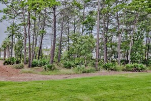 A grassy area with a row of tall trees and a building in the background. - Recovery Room | Steps from The Big Chill | Private Deck, Pools & Bikes (Inlet Beach)