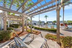 Zona junto a la piscina con sillones de descanso, una pérgola y una pileta.
