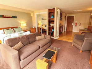 Ein Hotelzimmer mit Bett, Sofa, kleinem Tisch und Küchenzeile.