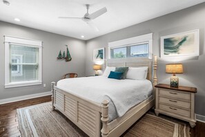 A bedroom with a bed, nightstands, a ceiling fan, and artwork on the walls. - Sandy Knickers | Pool | Gulf Views | Beach Access (Seacrest)