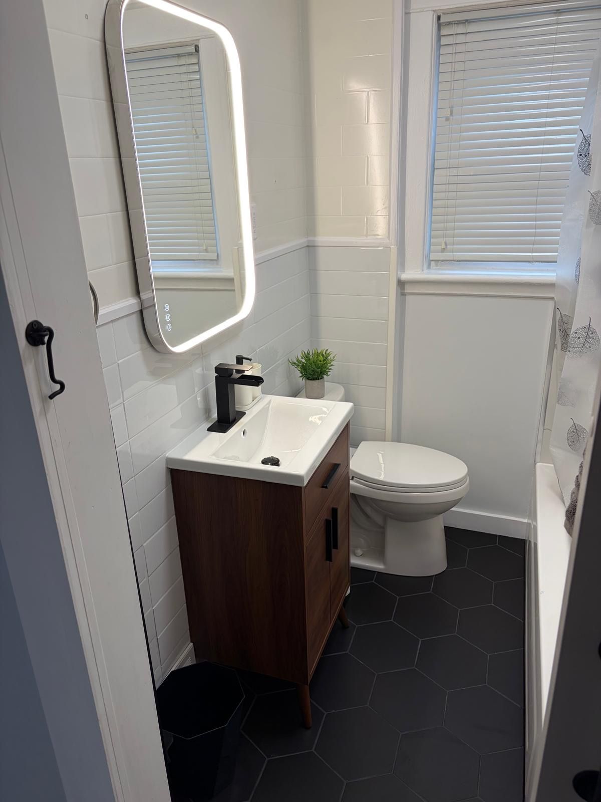 Ein modernes Badezimmer mit einem weißen Waschtisch, einer Toilette und einer Badewanne.