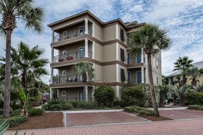 A multi-story residential building with balconies, surrounded by palm trees and a landscaped garden. - Sea Sanctuary | Pool | 3 Balconies | Near Beach (Seacrest Beach)