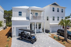 Ein zweistöckiges Haus mit Garage, Balkon und einem Golfwagen vor der Tür.