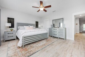 Ein Schlafzimmer mit einem Bett, Nachttischen, einer Kommode, einem Deckenventilator und einem Teppich.