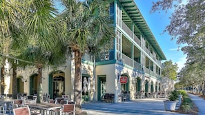 Un edificio con mesas al aire libre, palmeras y un letrero que indica un restaurante.
