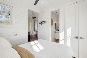 A bedroom with a bed, a ceiling fan, a window, and a door leading to a bathroom. - 🚲Stepping Stone Carriage House- Bikes- Inlet Beach🚲 (Inlet Beach)