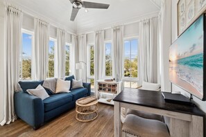 A spacious living room with a blue sofa, a wooden coffee table, and a TV mounted on the wall. - 🚲Stepping Stone Carriage House- Bikes- Inlet Beach🚲 (Inlet Beach)
