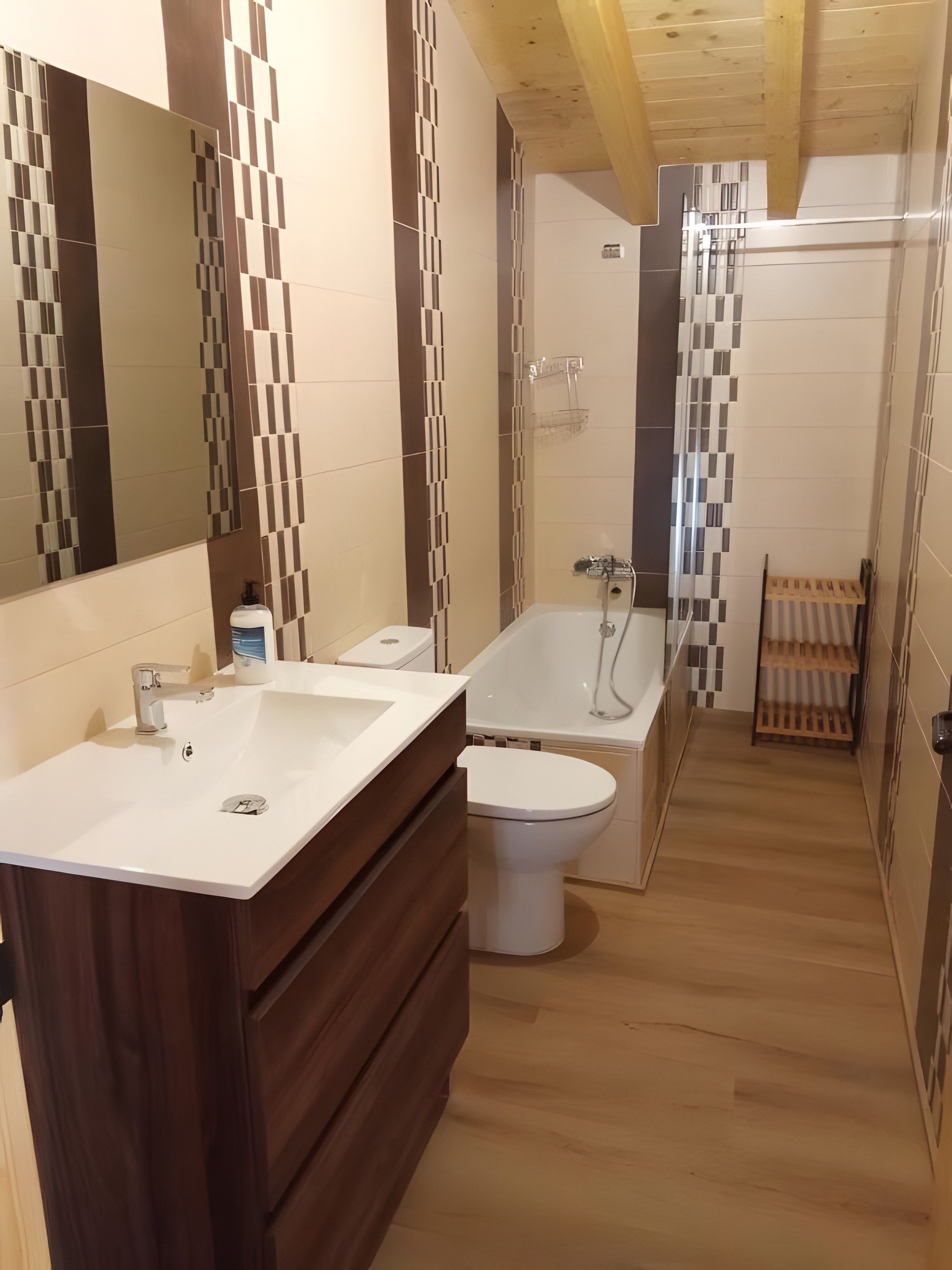 A modern bathroom with a wooden vanity, a bathtub, and a toilet.