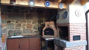 Una pared de piedra con un horno de ladrillo, armarios de madera y un lavamanos.