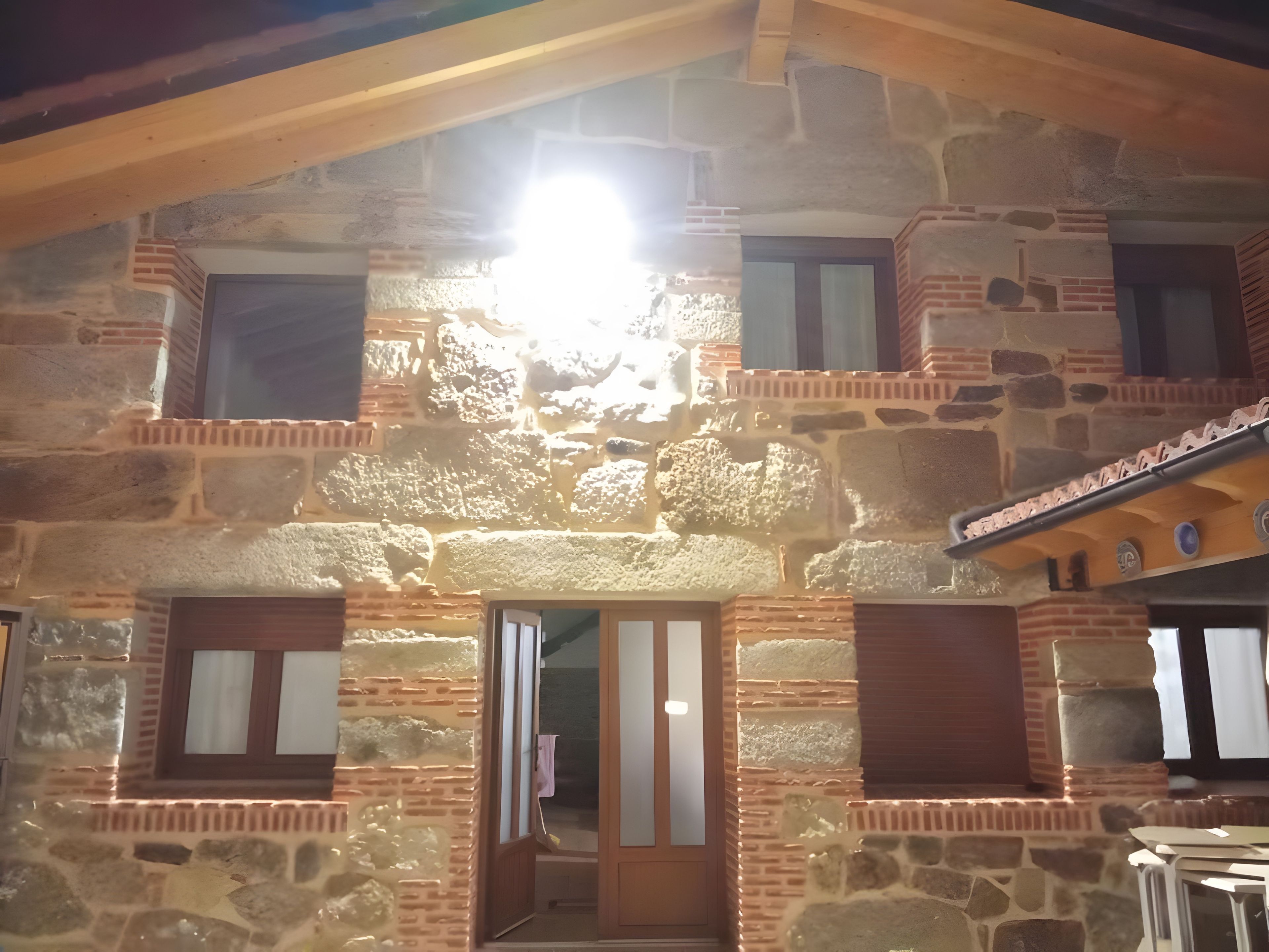 A stone building with a wooden balcony and a door leading to an interior space.