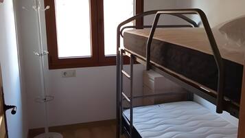 A bunk bed room with a window, a coat rack, and a bedside table.