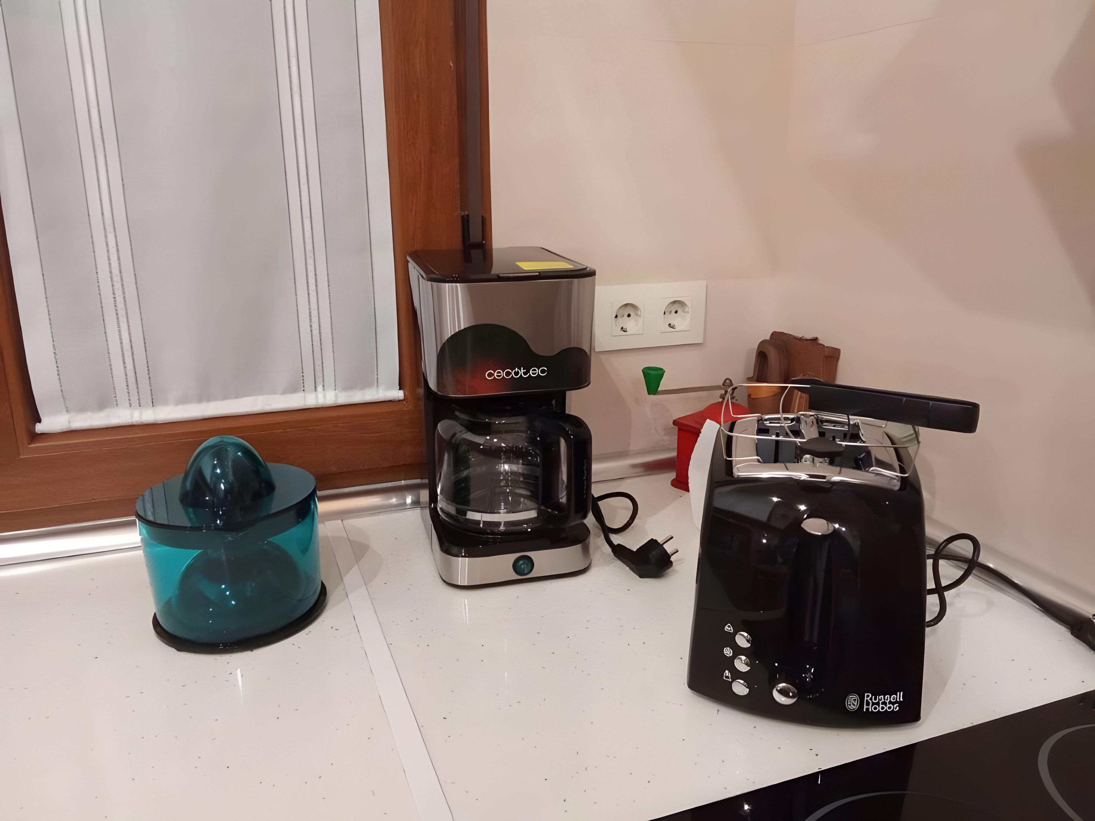 En köksbänk med en kaffebryggare, en juicepress och en brödrost.