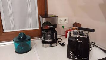 Una encimera de cocina con cafetera, extractor de jugos y tostadora.