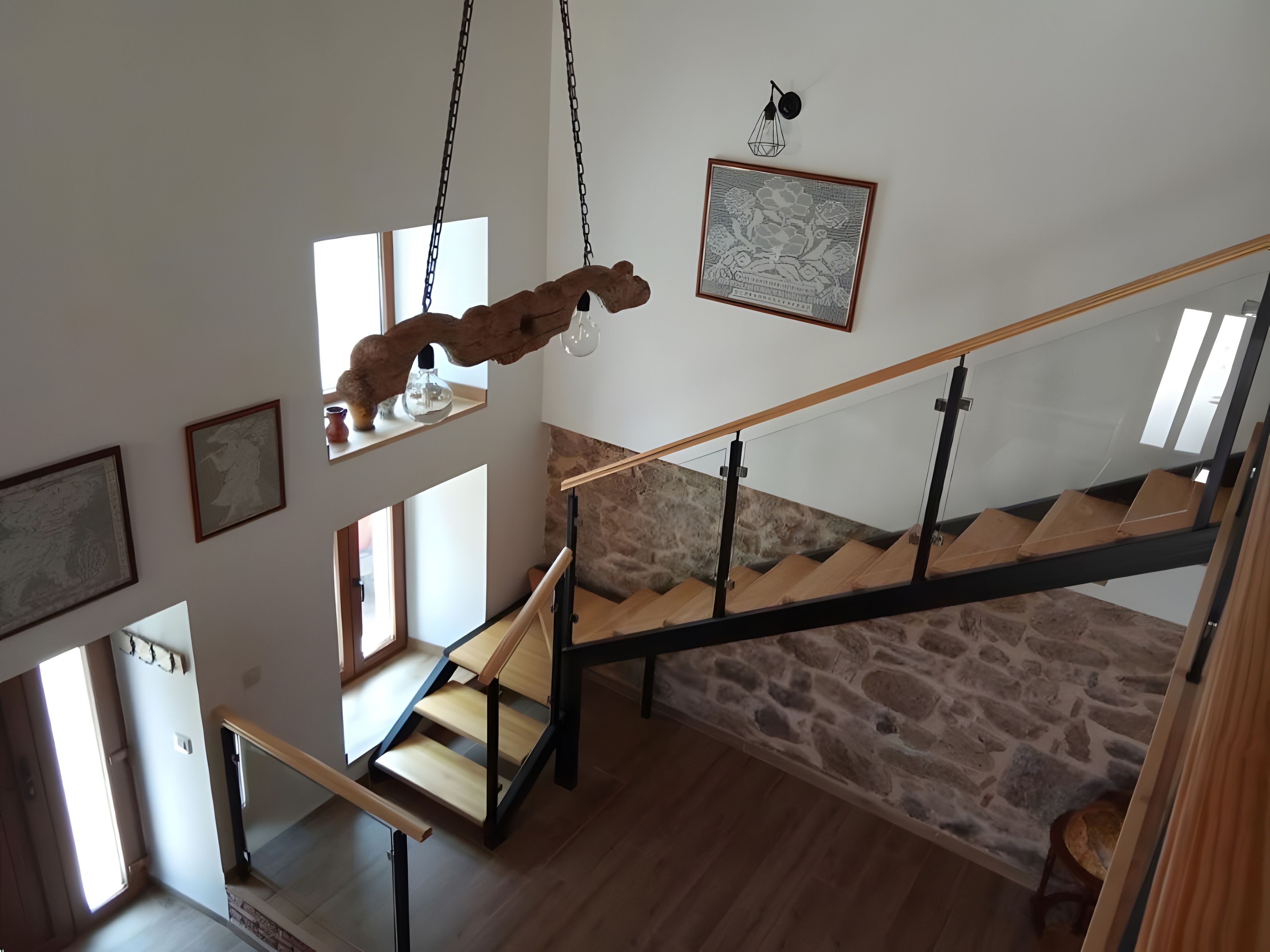 A staircase with a wooden handrail and stone wall.