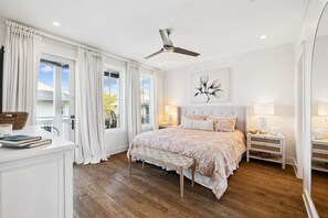 Ein Schlafzimmer mit einem Bett, Nachttischen, einem Deckenventilator und einem Fenster mit Vorhängen.