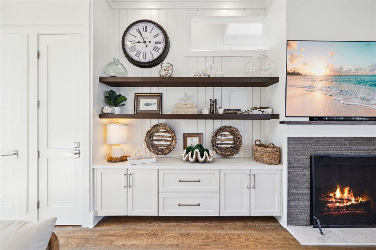 Un salon avec une cheminée, un téléviseur et une horloge au mur.