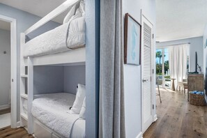 A bunk bed room with a view of the outdoors, a window with curtains, and a door leading to another room. - ☀️Sun Stone | Steps from Beach | Pool | Sleeps 6☀️ (Santa Rosa Beach)