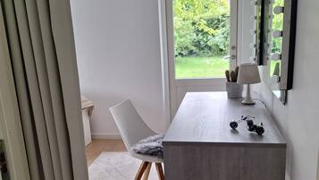 A modern room with a large window, a desk with a lamp, and a chair.