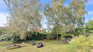A backyard with a swing set, a red bean bag, and a bicycle rack.