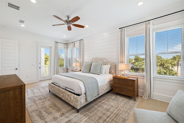 A bedroom with a bed, bedside tables, a ceiling fan, and large windows. - 🌴Sandcastle at Bluewater Landing | Golf Cart & Bikes Included | Sleeps 10 (Santa Rosa Beach)