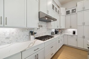 A modern kitchen with white cabinets, a marble backsplash, and a stainless steel stove. - 🌴Sandcastle at Bluewater Landing | Golf Cart & Bikes Included | Sleeps 10 (Santa Rosa Beach)