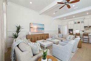 A spacious living room with a sofa, coffee table, and a painting of a sunset. - 🌴Sandcastle at Bluewater Landing | Golf Cart & Bikes Included | Sleeps 10 (Santa Rosa Beach)