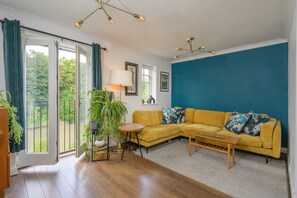 A living room with a yellow sofa, a coffee table, and a large window with curtains. - Townhouse on the River, Decking & Private Parking (Bristol City)