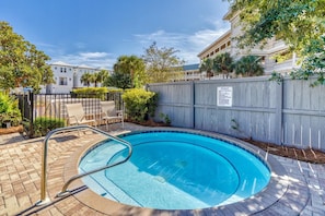 A swimming pool with a wooden fence and a sign, surrounded by a brick patio and greenery. - Village of South Walton F307-Vitamin Sea | Condo | Pool & Hot Tub | Sleeps 8 (Alys Beach)