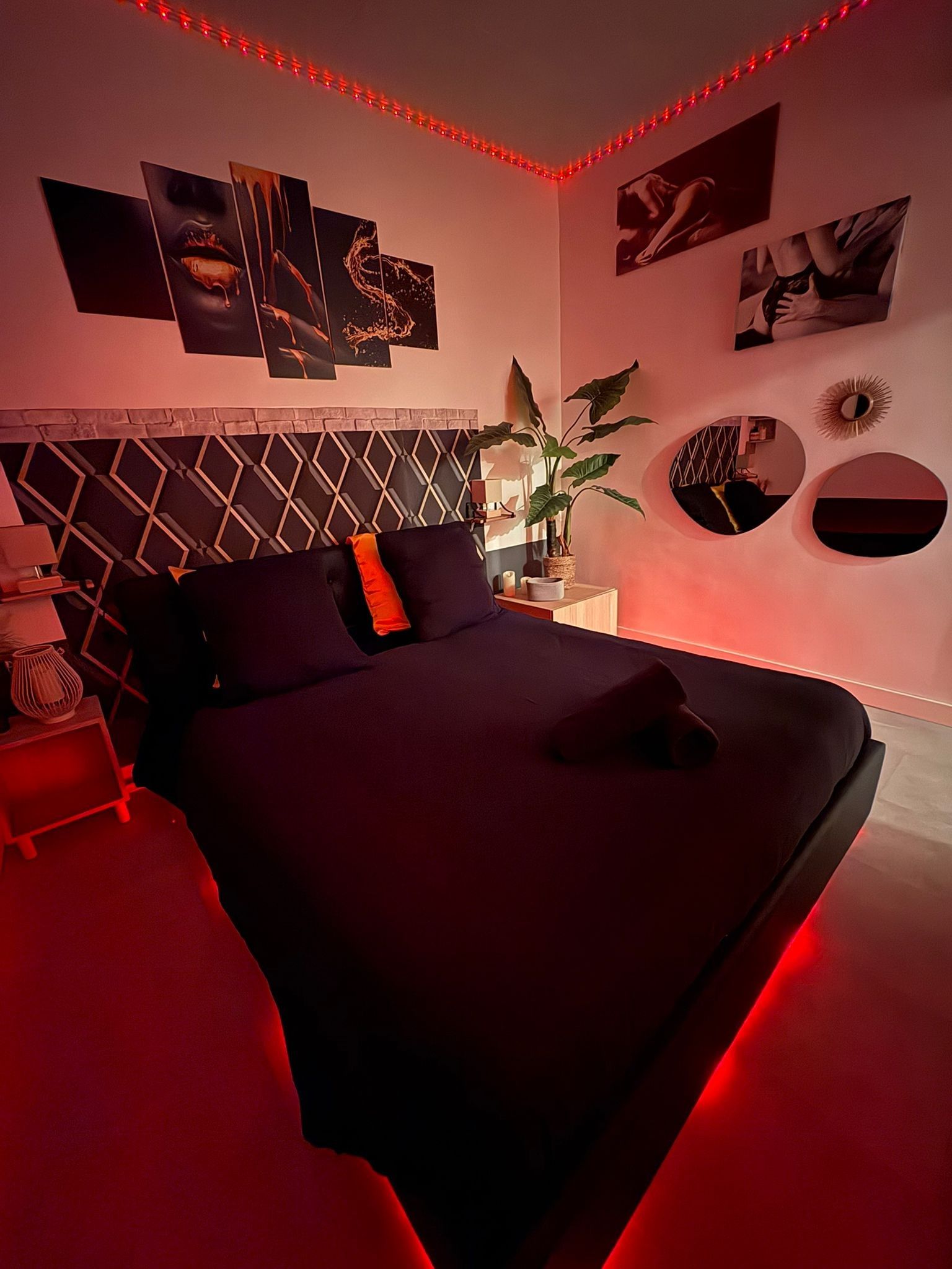 A bedroom with a bed, a nightstand, a lamp, and wall art.