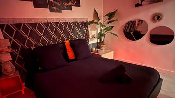 A bedroom with a bed, a nightstand, a lamp, and wall art.
