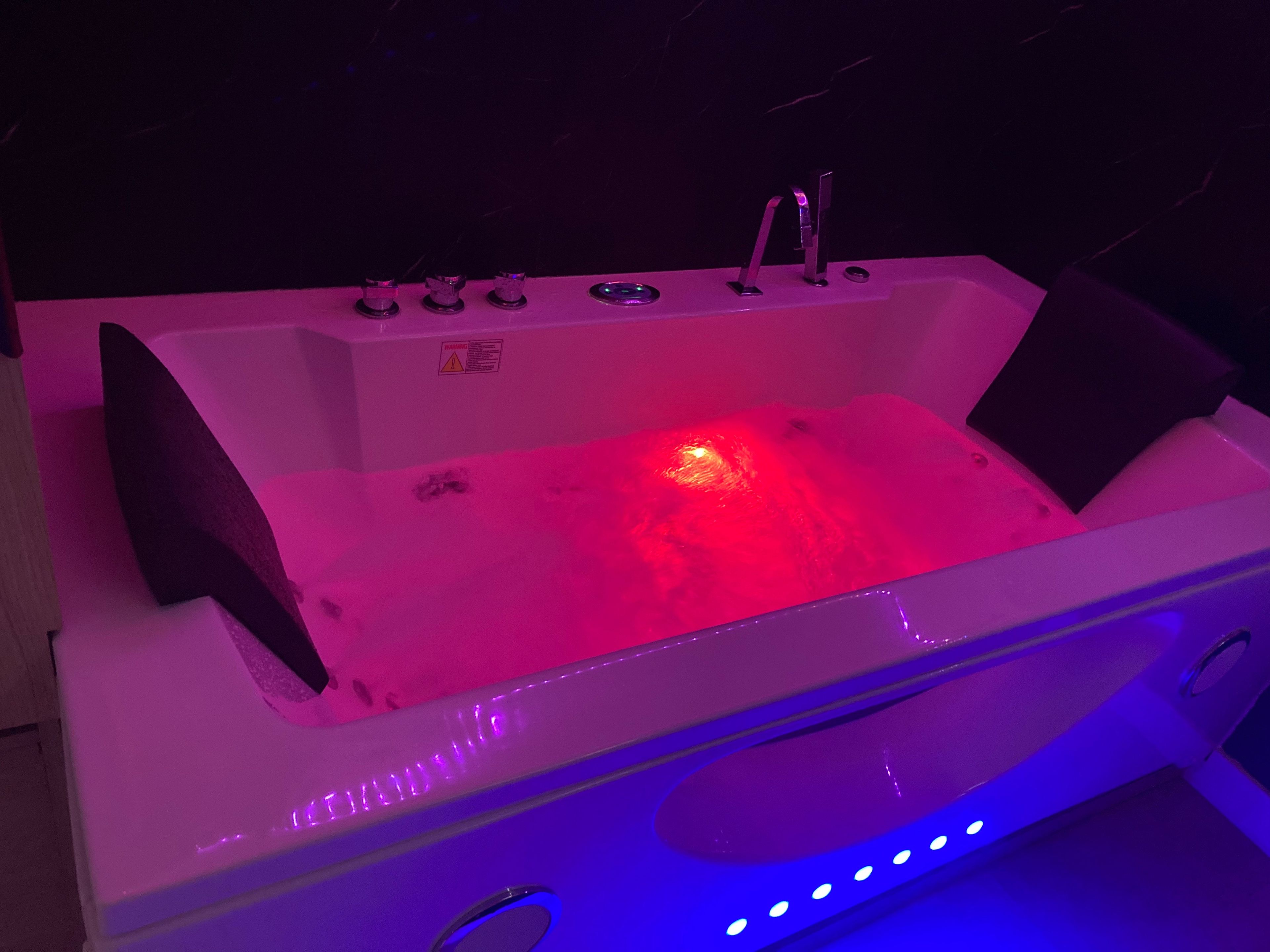 Une baignoire blanche avec une lumière rouge, un robinet et un panneau de commande.